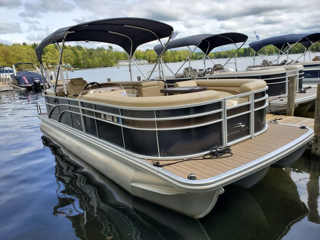 Black & grey 2018 Bennington 23 SSRCX boat parked at a dock on a lake next to other boats.